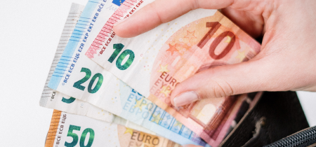 A hand holding a stack of euro notes
