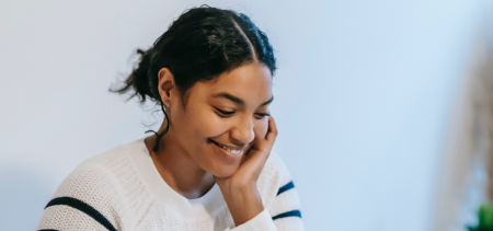 A girl smiling and resting her hand on her face