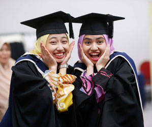 Two DBS students wearing graduation gowns